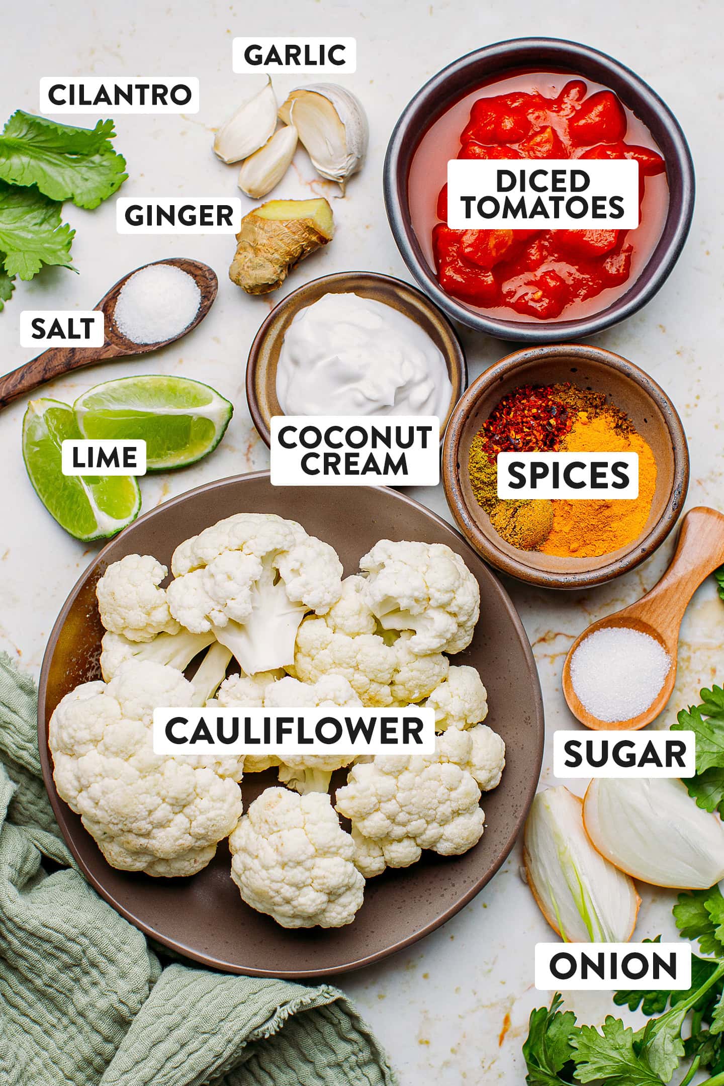 Ingredients like cauliflower, diced tomatoes, spices, and coconut cream.