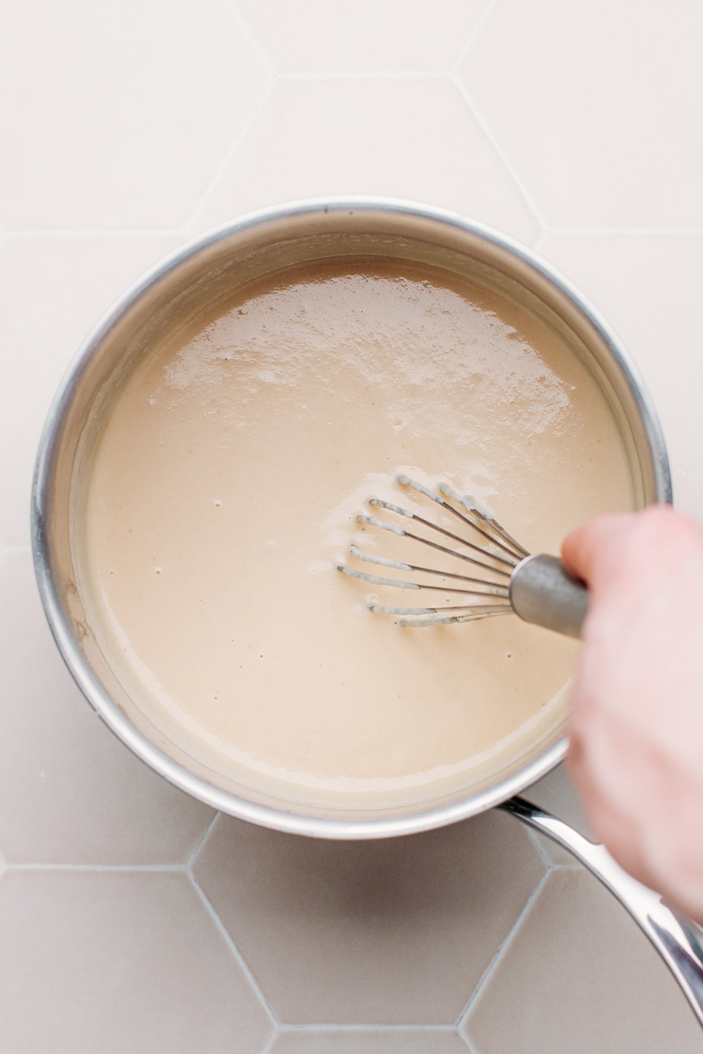 Whisking vegan cheese sauce in a saucepan.