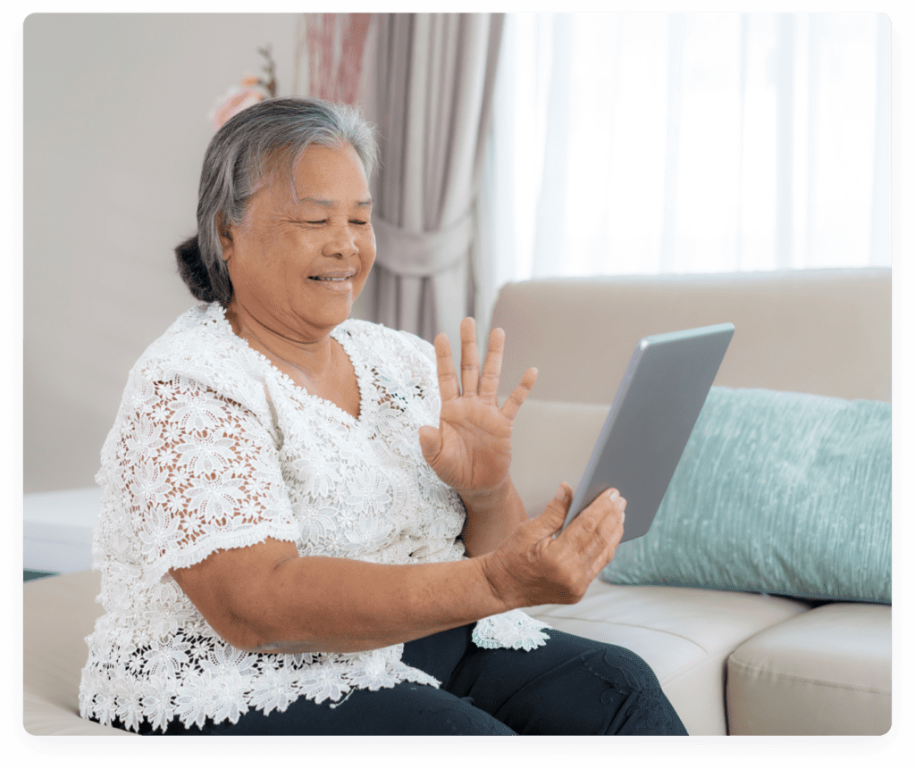 Older adult smiling and waving at a tablet