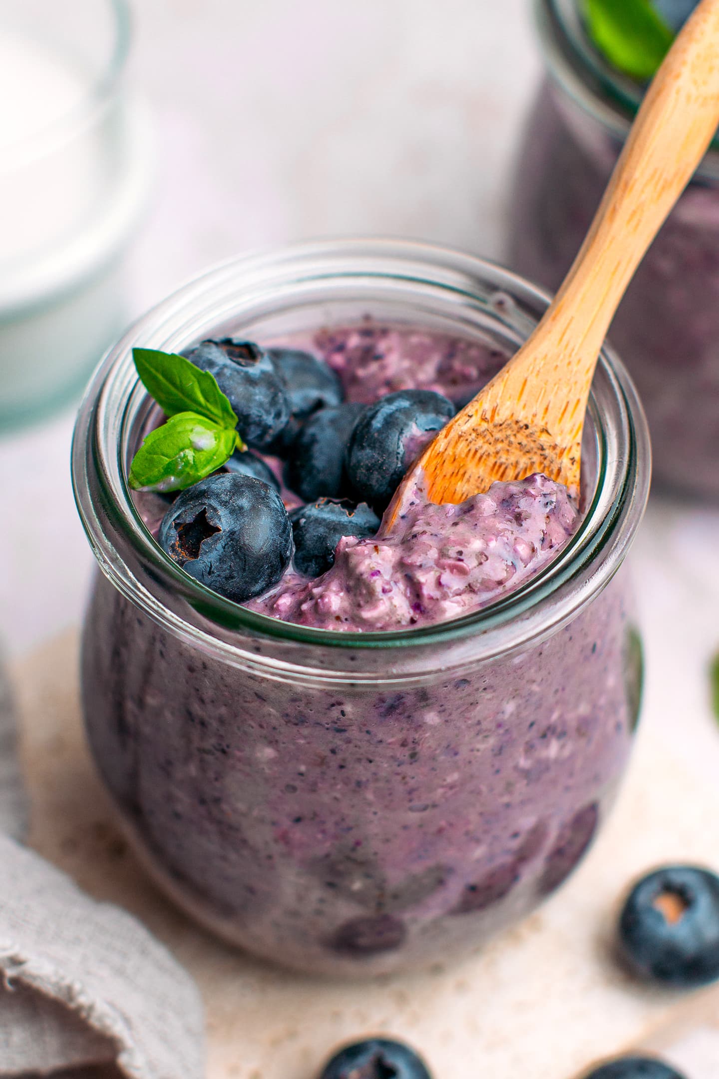 Blueberry oats with fresh blueberries and basil leaves in a small jar.