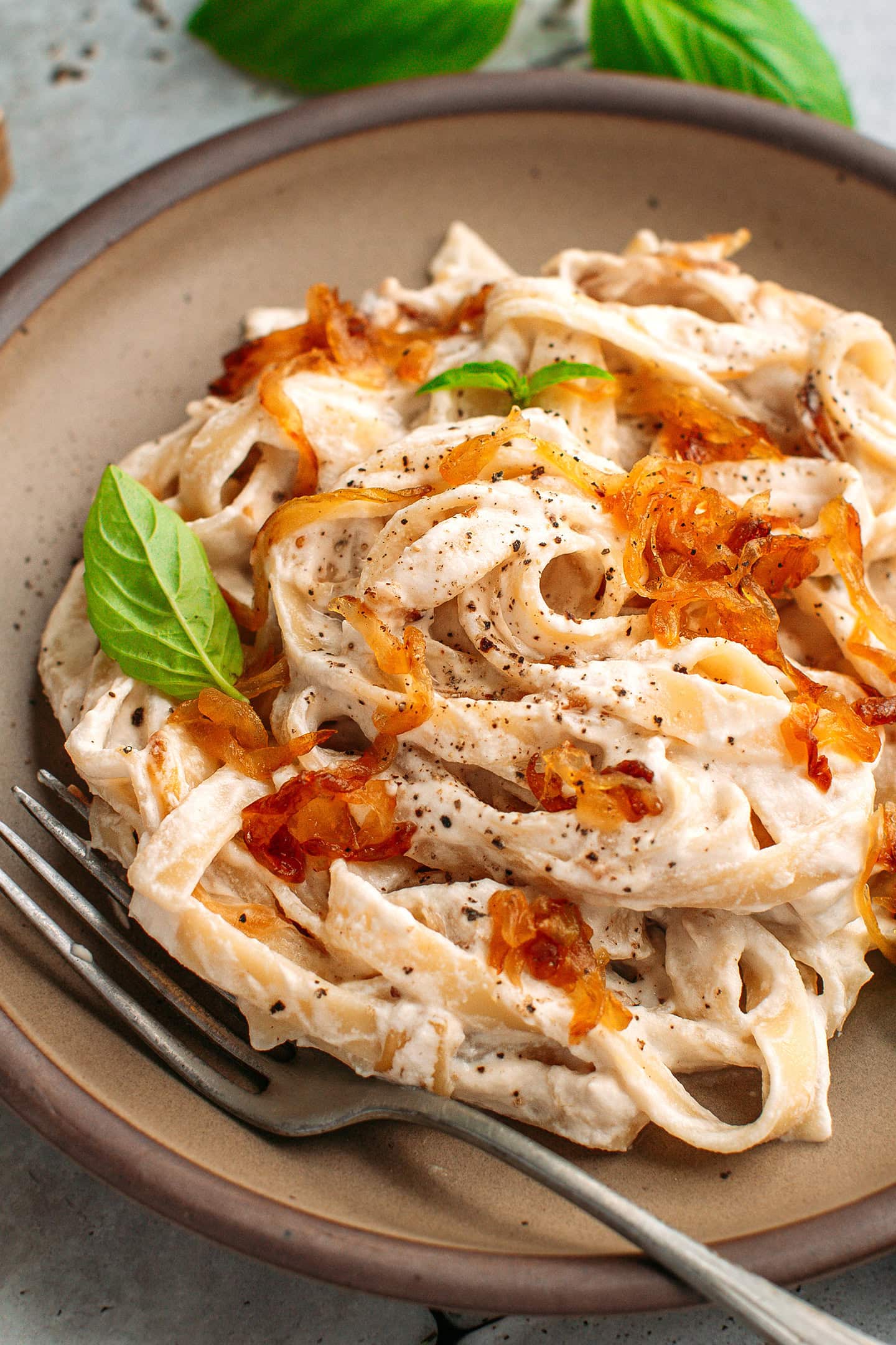 Close-up of pasta tossed with cashew cream and caramelized onions on a plate.