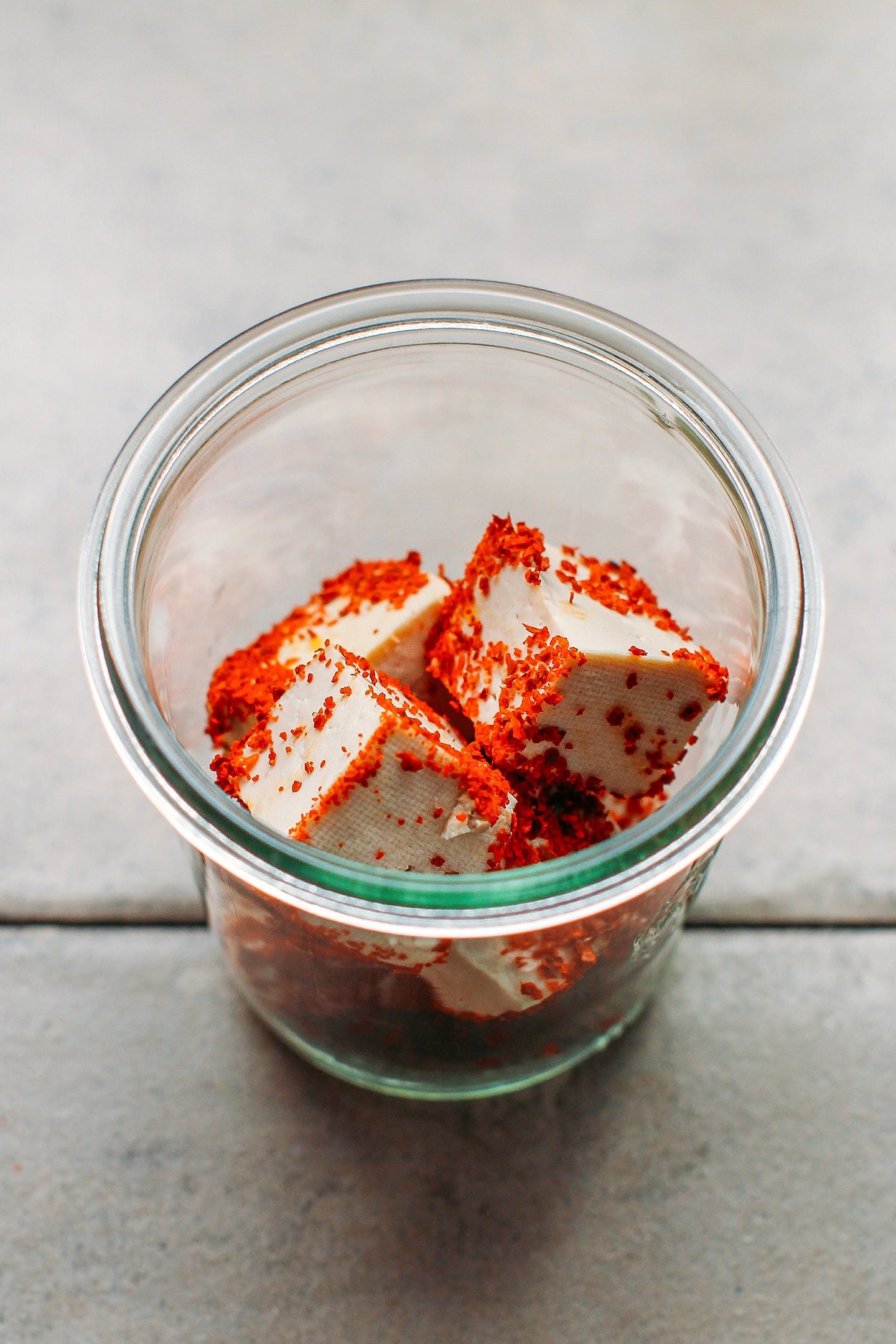 Cubes of tofu coated with chili powder in a glass jar.