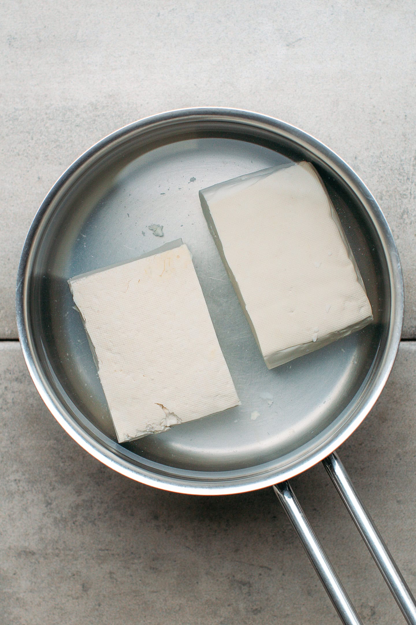 Two blocks of tofu in a pot of boiling water.