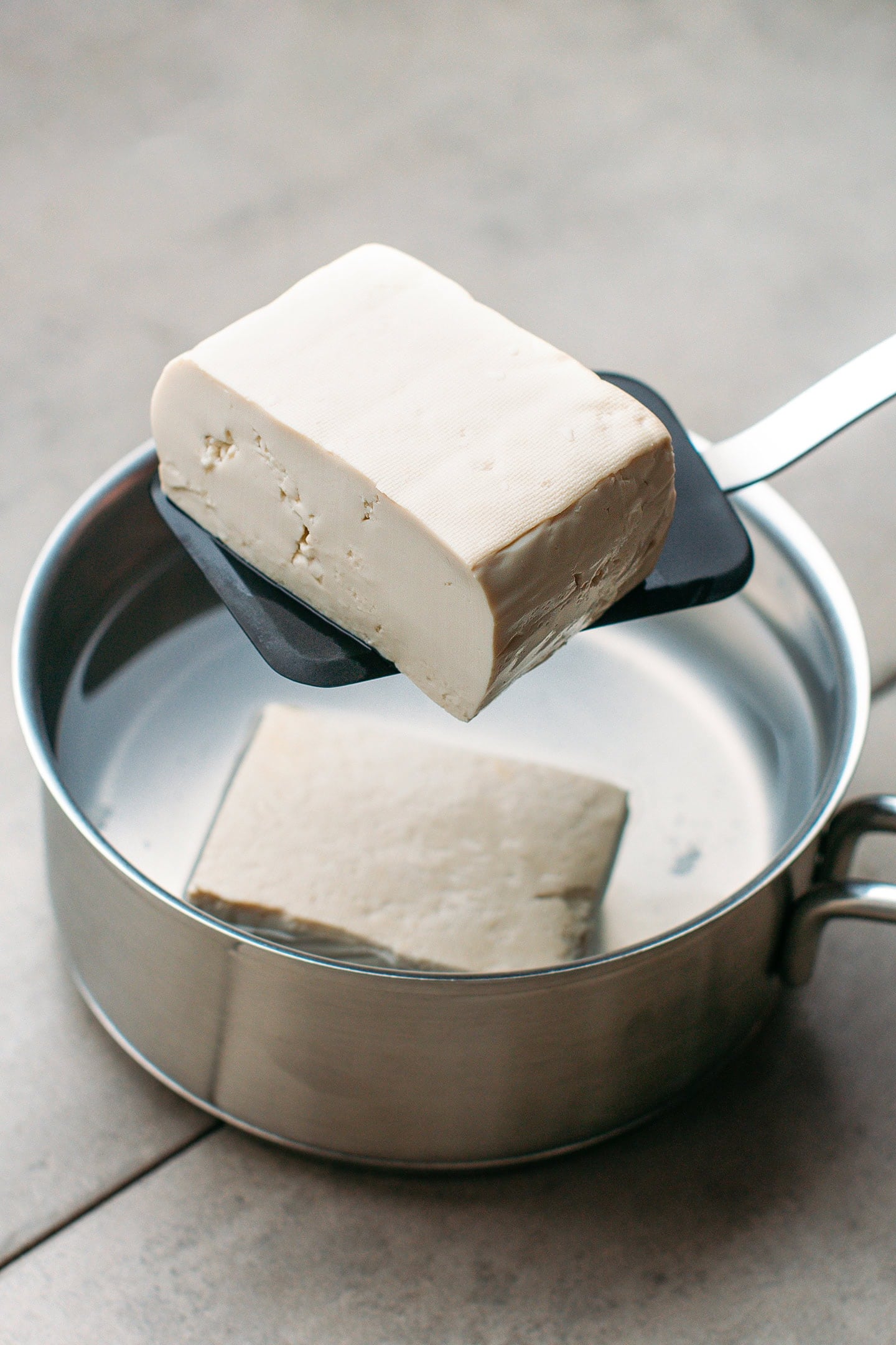 A piece of tofu on a spatular.