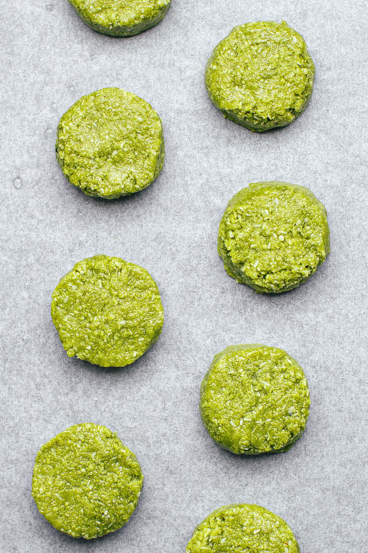Unbaked matcha and coconut cookies on a baking sheet.