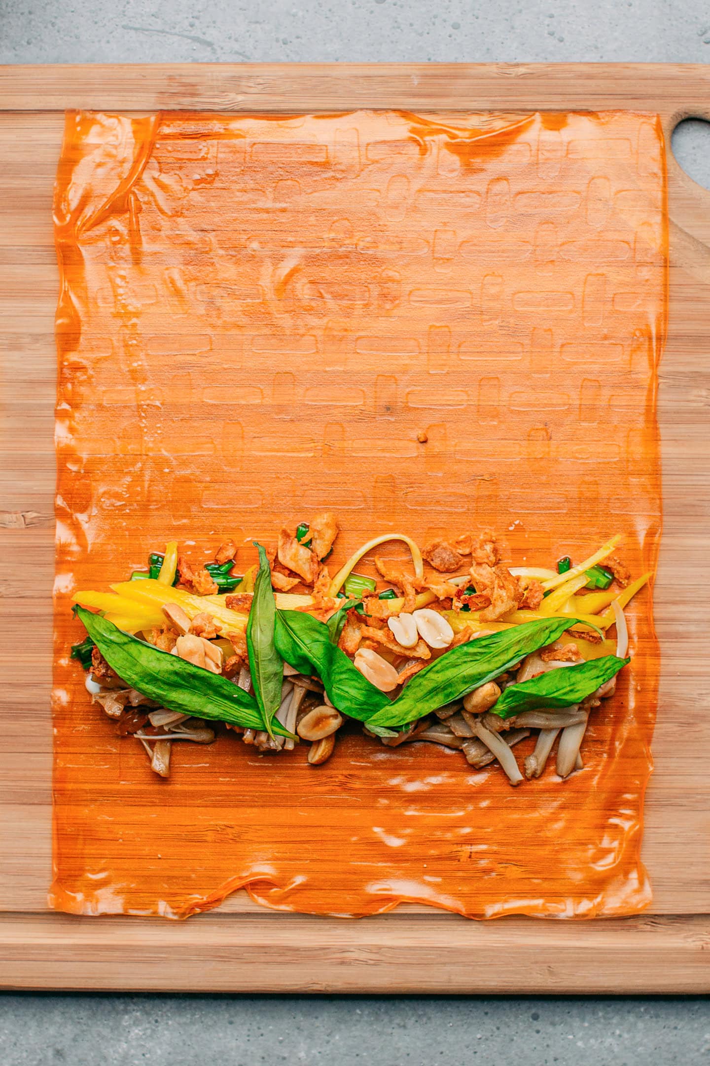 Rice paper sheet topped with shredded mango, jackfruit, and fresh herbs.