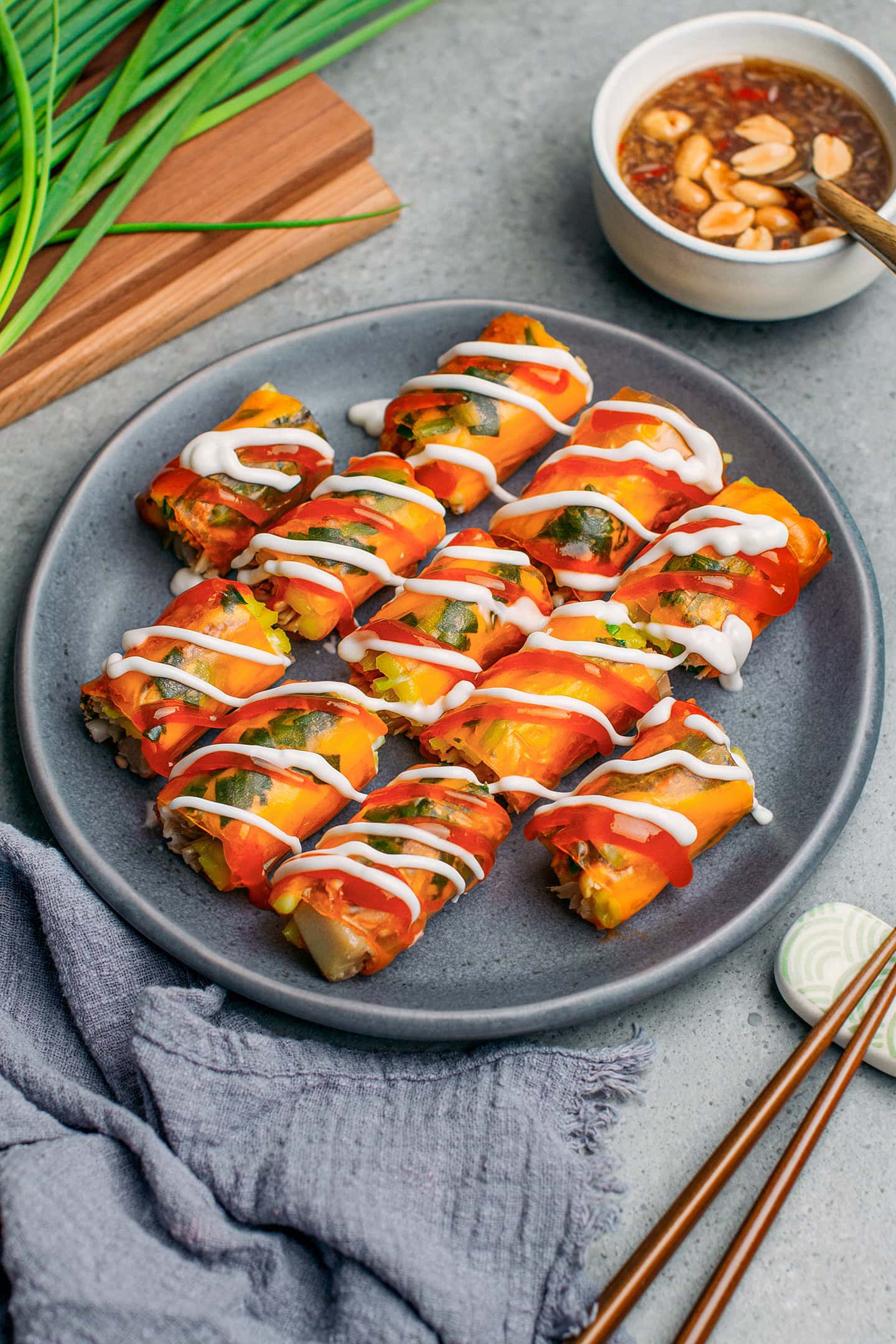 Rice paper rolls drizzled with sweet chili sauce and mayo on a plate.