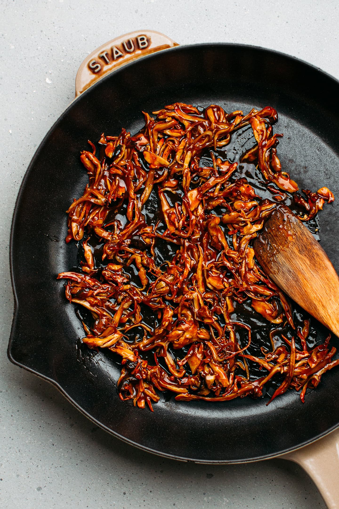 Pulled mushrooms coated with BBQ sauce in a skillet.