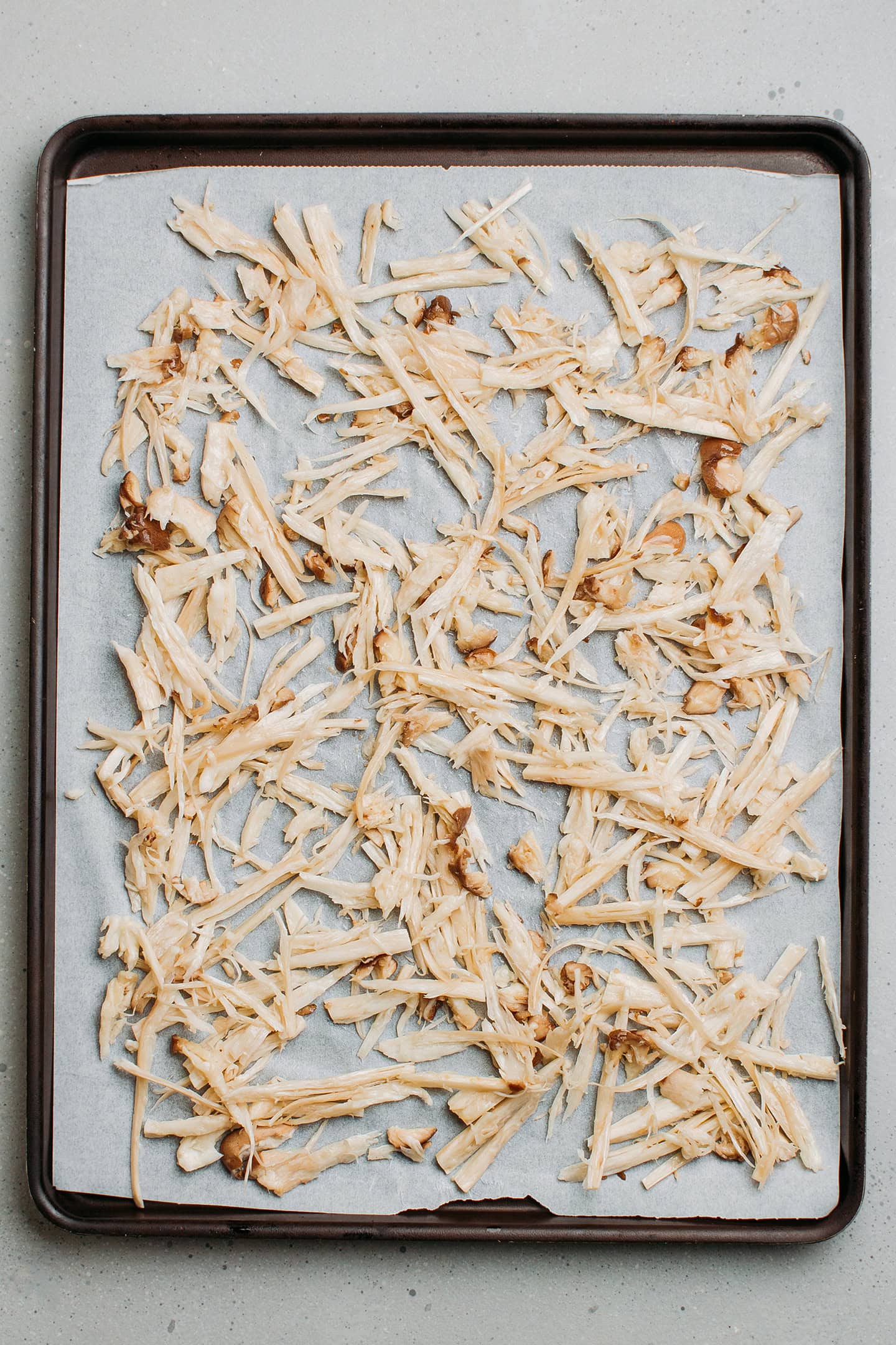 Shredded mushrooms spread on a baking sheet.