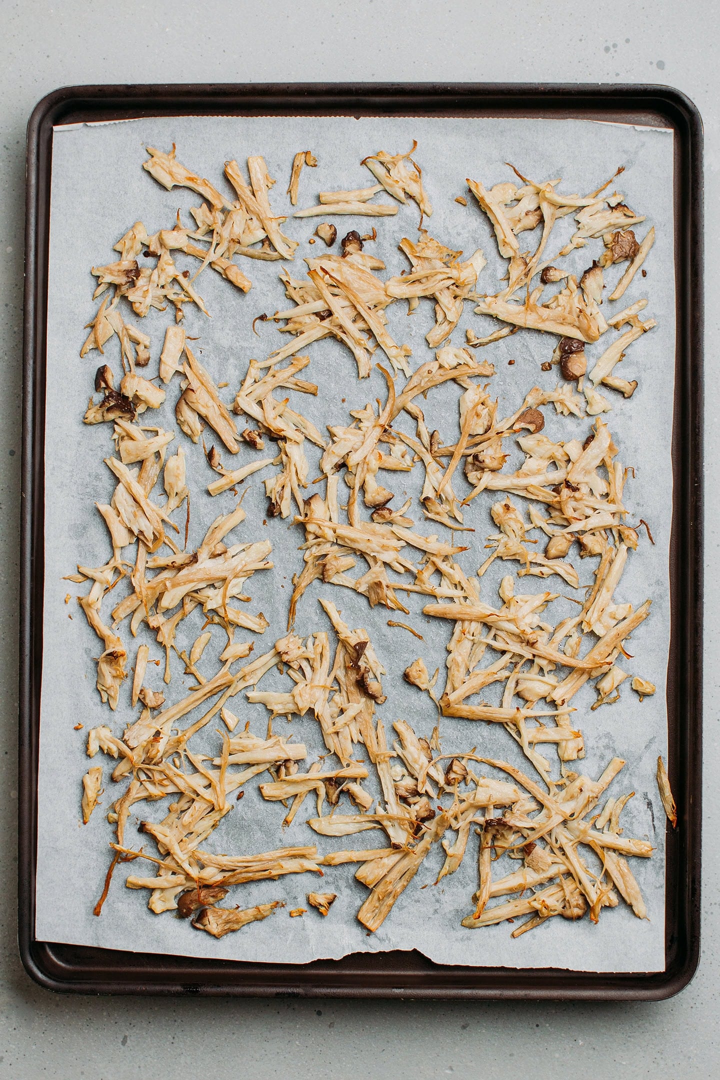 Baked shredded mushrooms on a baking sheet.