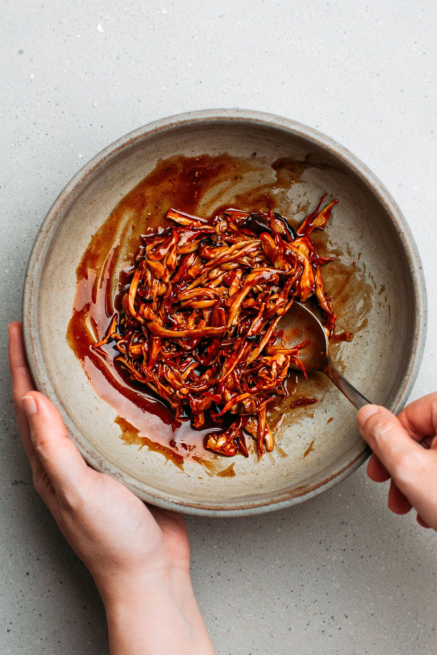 Coating pulled mushrooms with barbecue sauce.