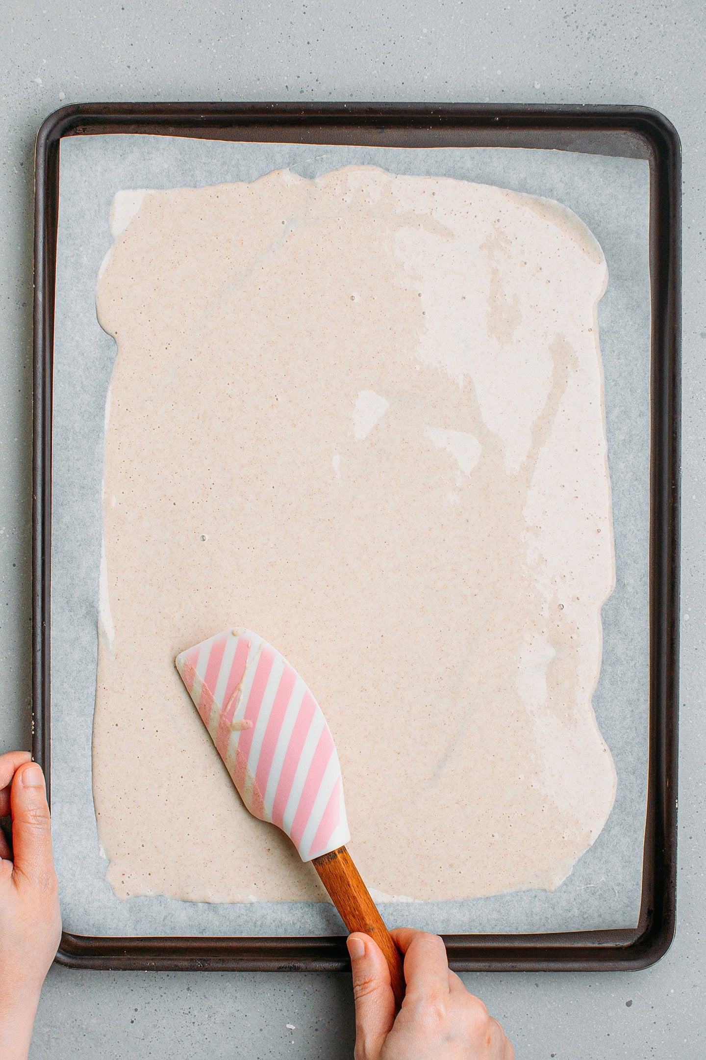 Spreading buckwheat batter into a thin layer on a baking sheet.