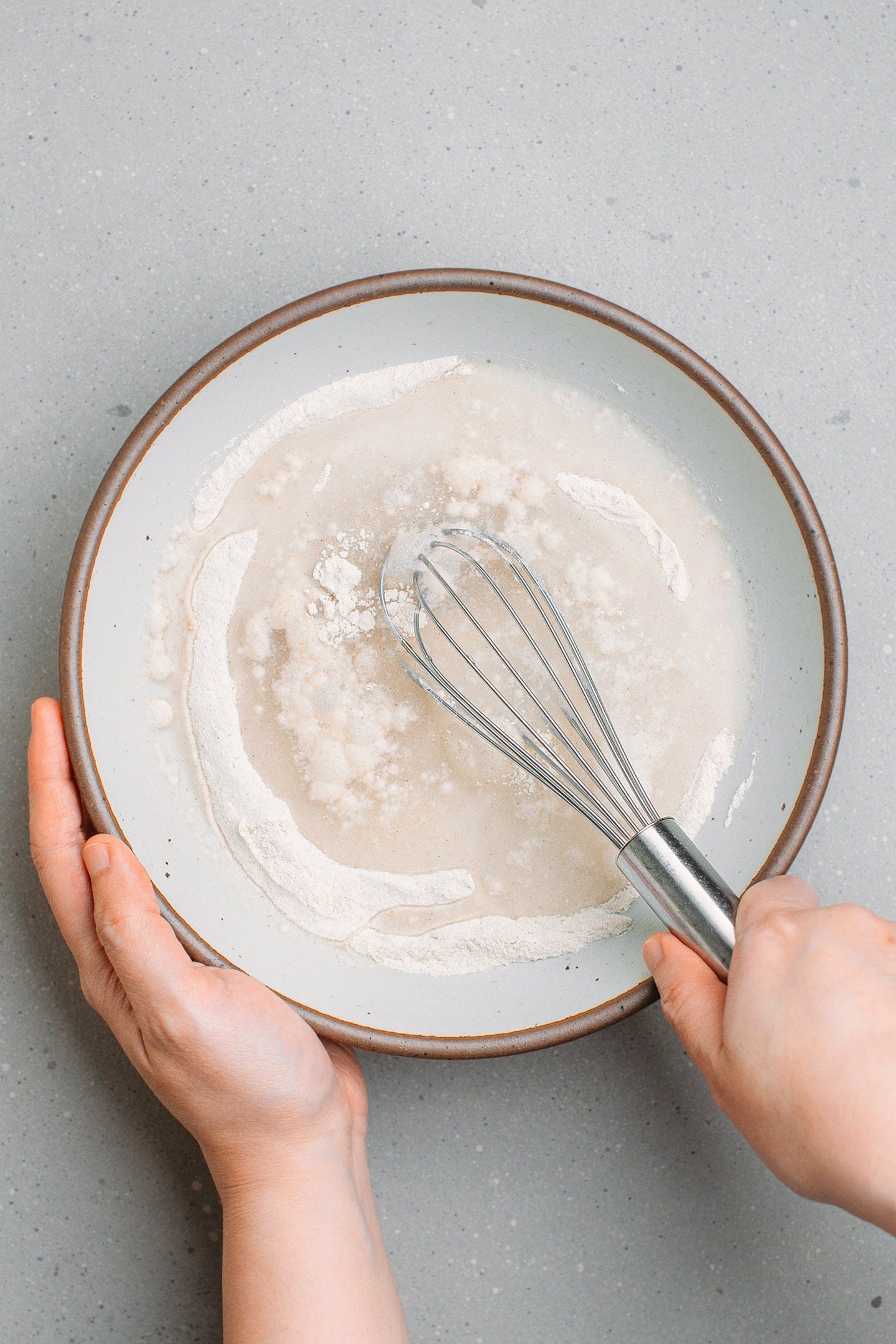 Whisking buckwheat flour with water and salt in a mixing bowl.