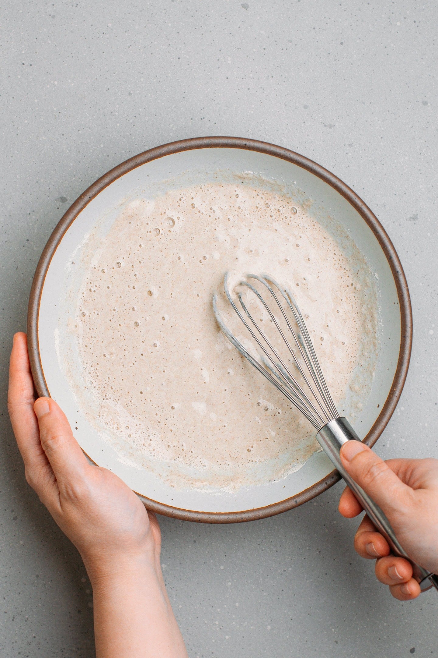 Whisking buckwheat flakes batter in a mixing bowl.