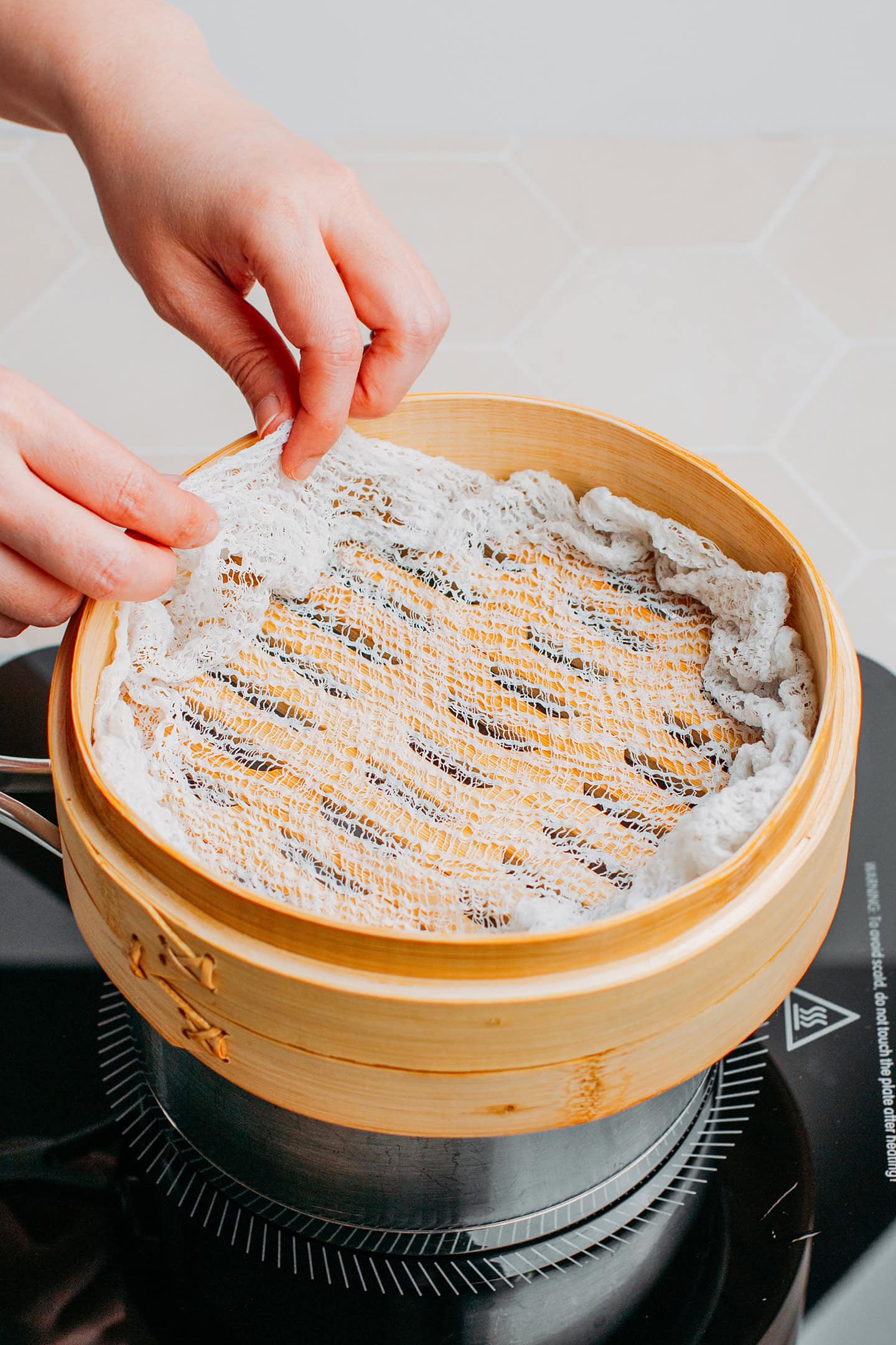 Arranging a cheesecloth in a bamboo basket steamer.