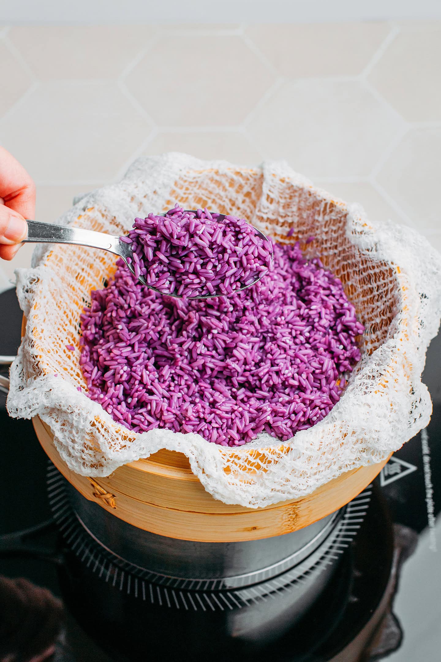 Adding soaked sticky rice to a bamboo basket steamer.