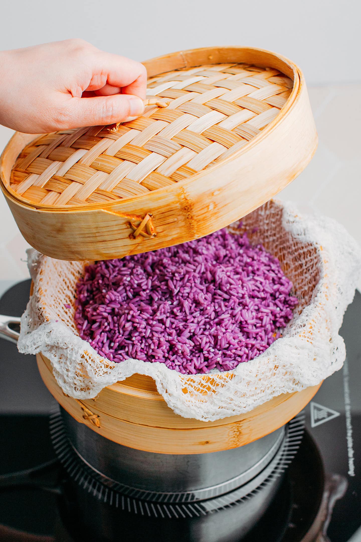 Closing a bamboo steamer basket with a lid.