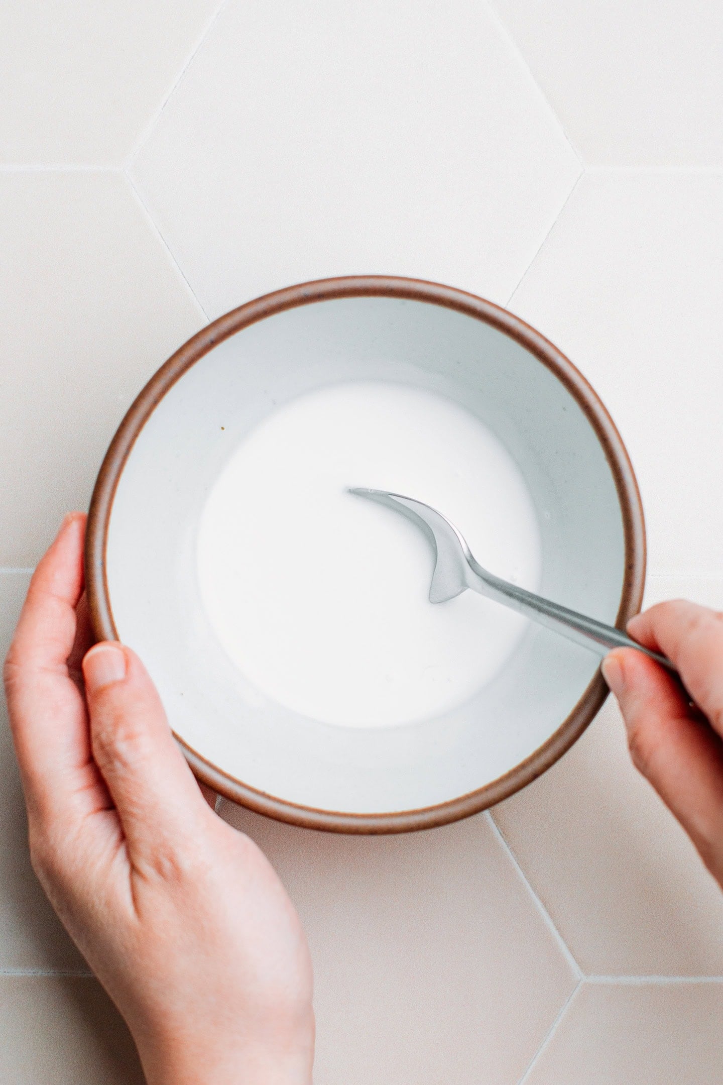 Stirring coconut milk with sugar and salt in a small bowl.