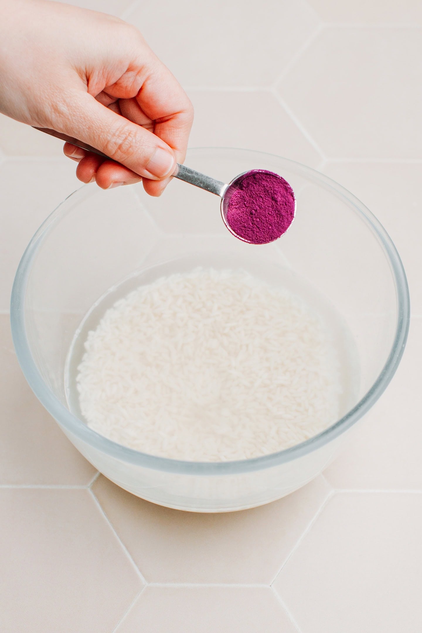 Adding ube powder to a bowl of rice.