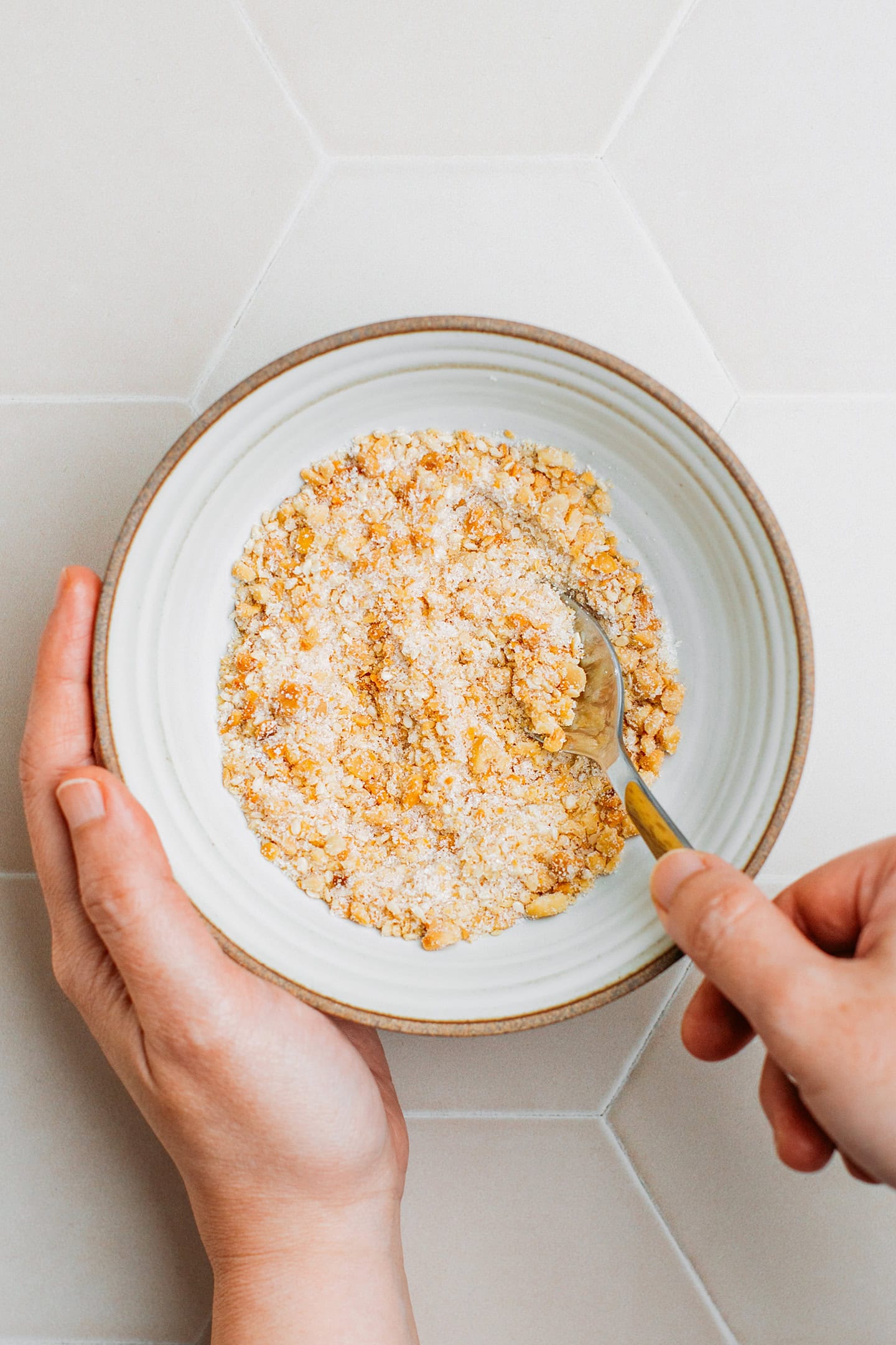 Mixing ground peanuts with toasted sesame seeds and sugar.
