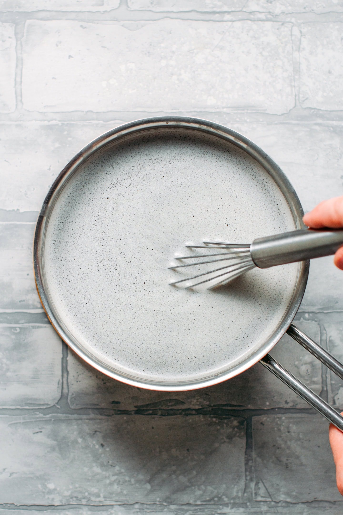 Whisking black sesame milk in a saucepan.
