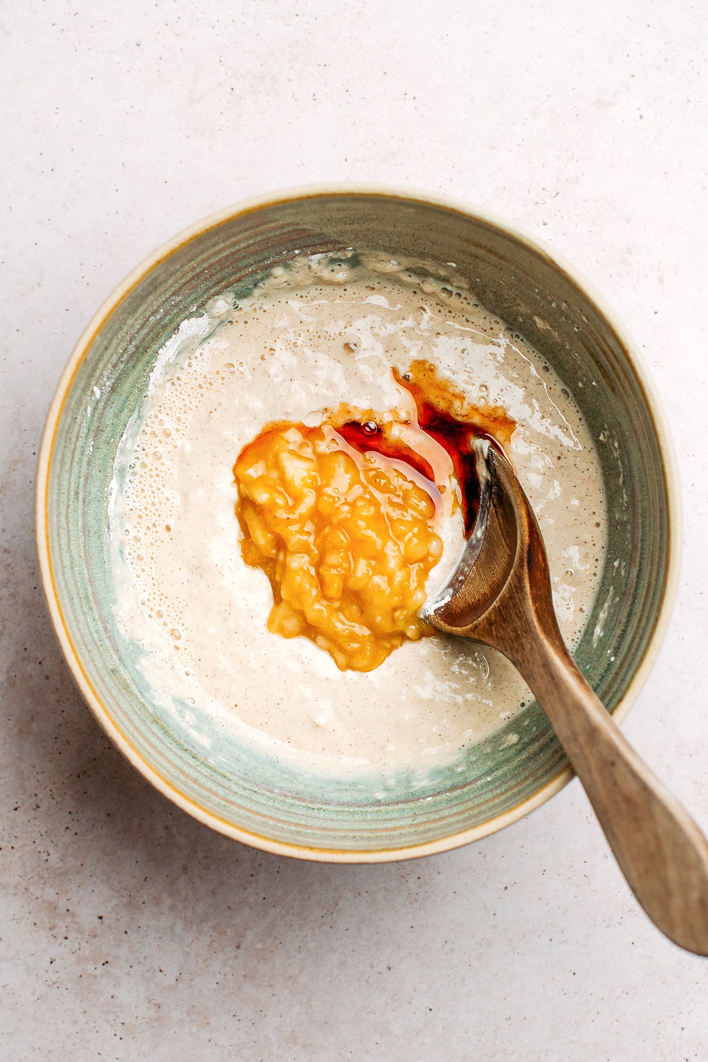 Mashed bananas and pancake batter in a bowl.