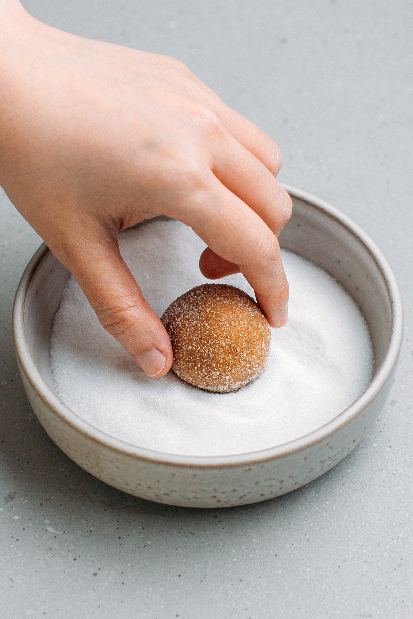 Rolling a ball of cookie dough in granulated sugar.