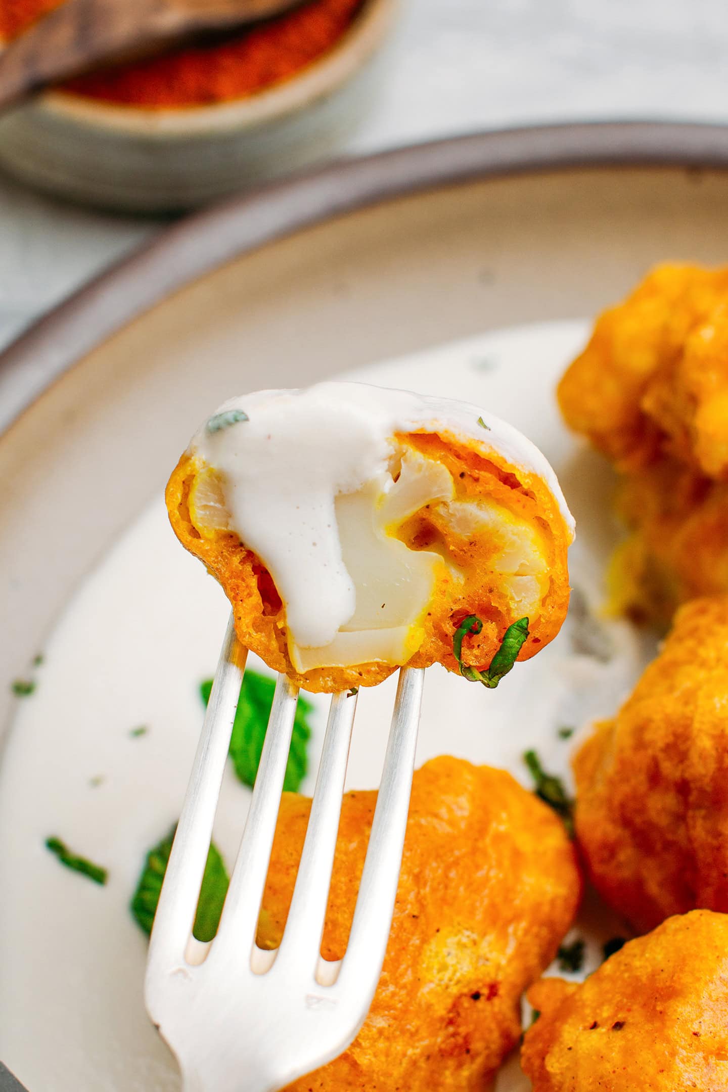 Close-up of a cauliflower florets dipped in a ginger sauce.