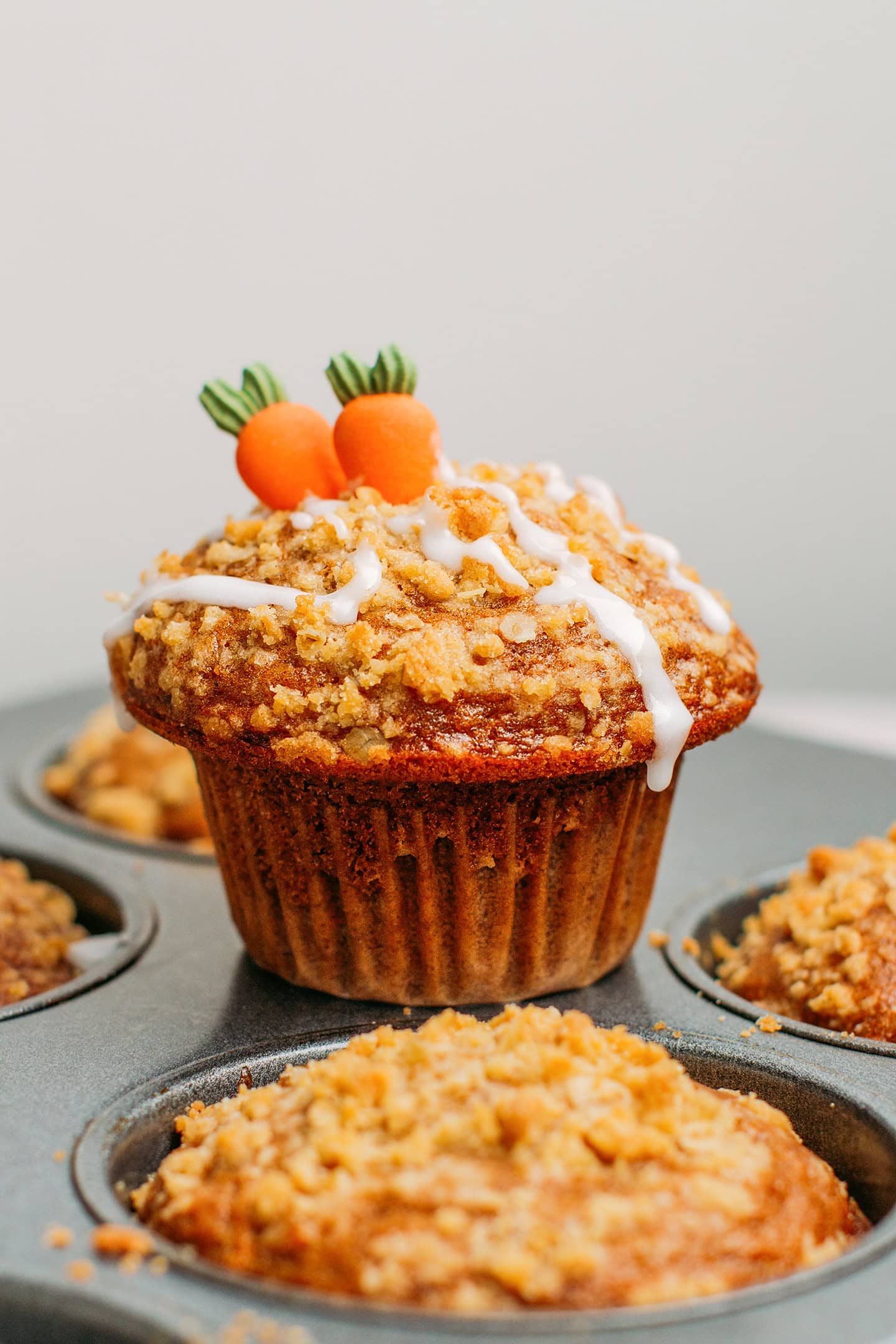 Carrot cake muffin glazed with icing on a muffin pan.