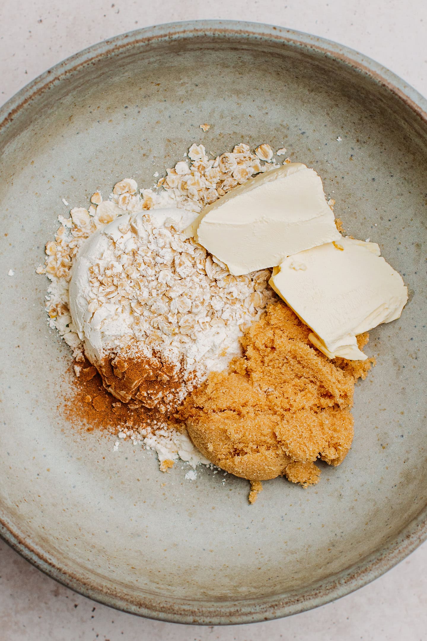 Butter, sugar, flour, and oats in a mixing bowl.