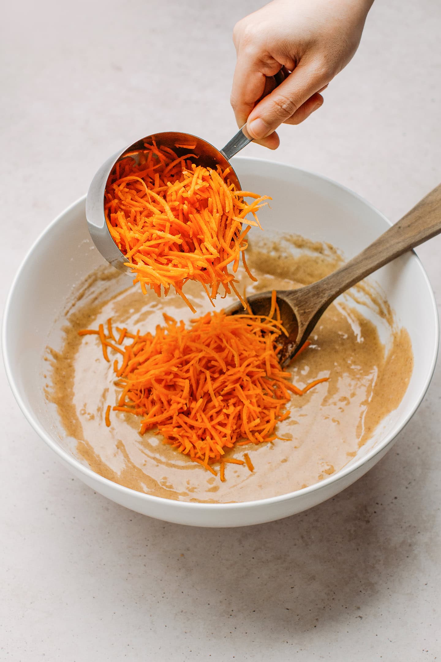 Adding grated carrots to a muffin batter.
