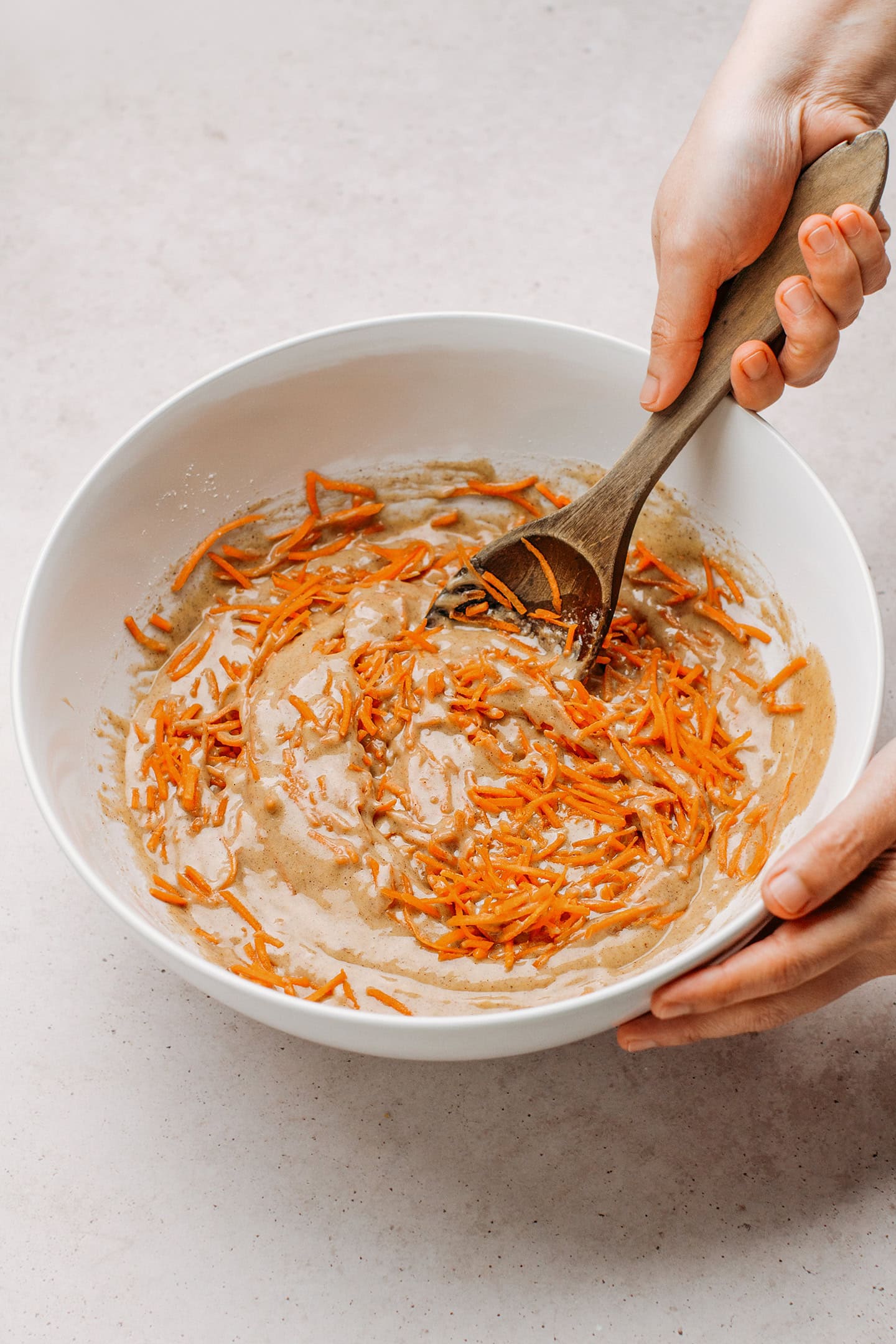 Incorporating grated carrots into a muffin batter.