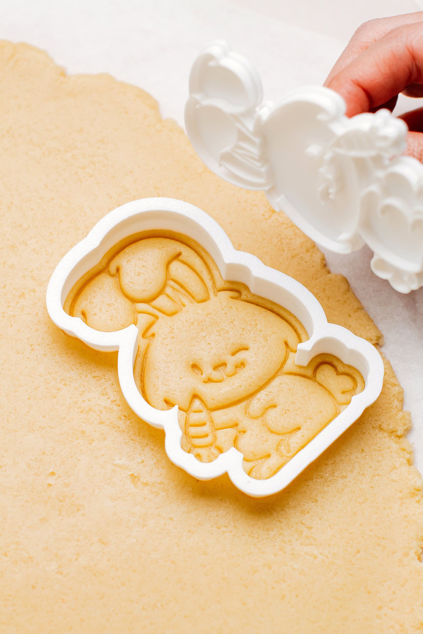 Making a bunny-shaped sugar cookie using a cookie cutter.