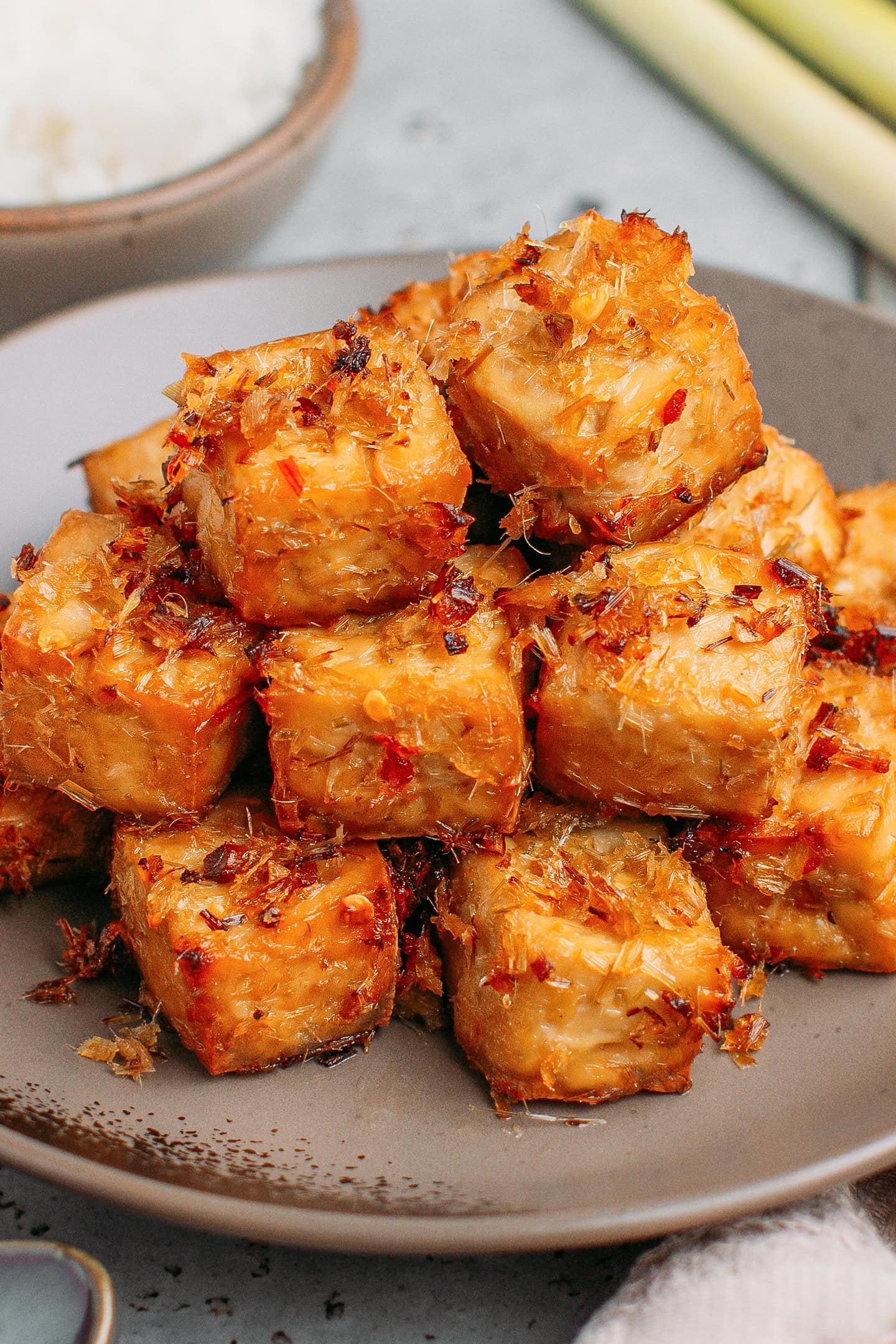Stacked lemongrass tofu cubes on a small brown plate.