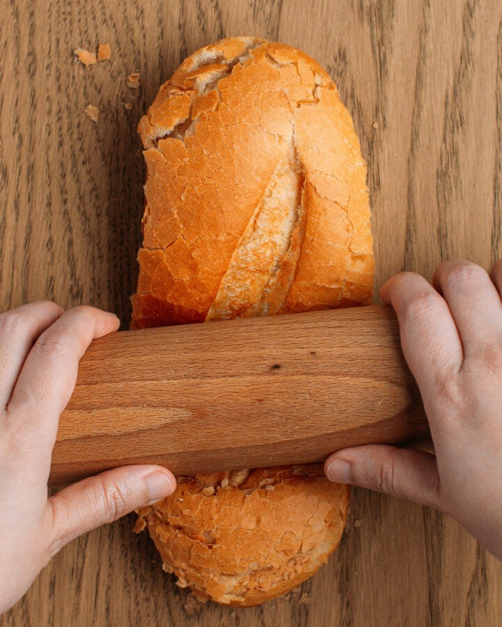 Flattening banh mi bread with a rolling pin.