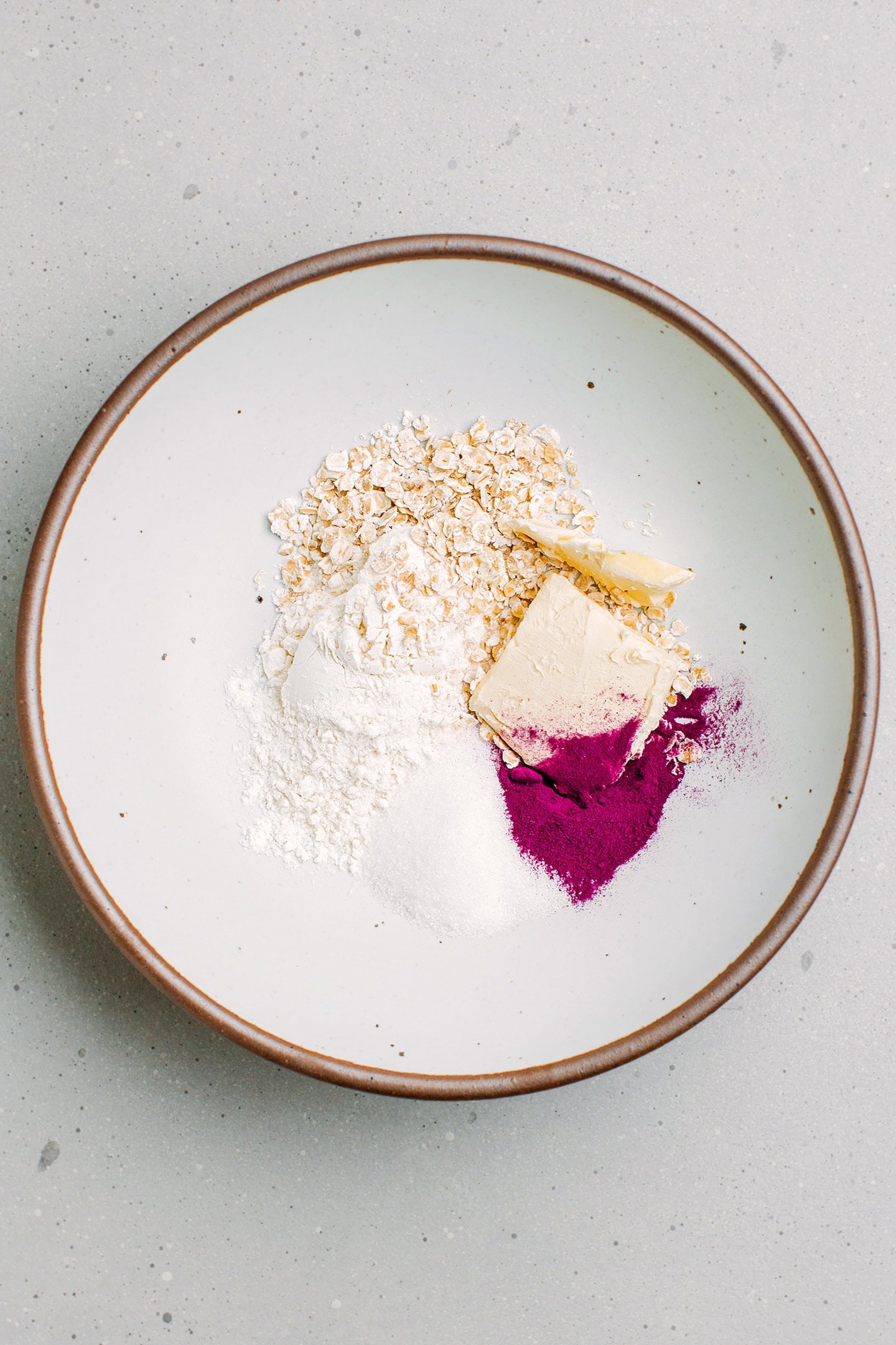 Flour, oats, butter, and ube powder in a bowl.