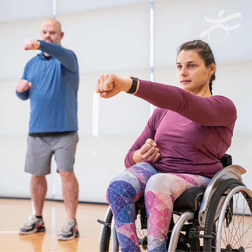 Man standing and woman seated in her wheelchair doing arm exercises
