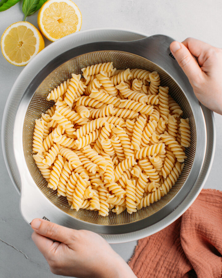 Draining fusilli pasta using a large sieve.