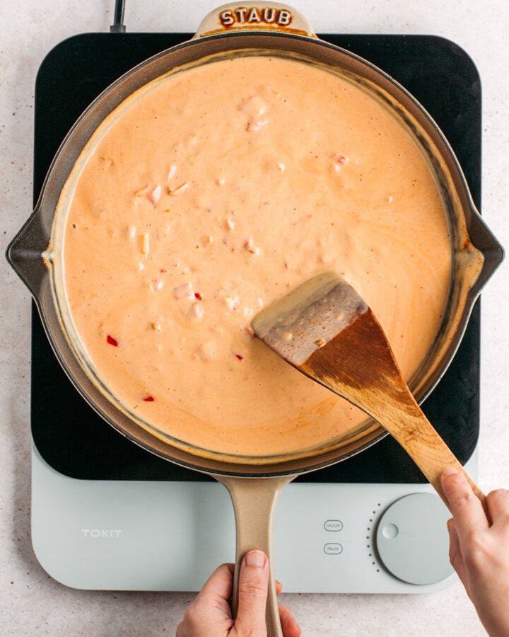 Stirring coconut milk peanut sauce in a skillet.