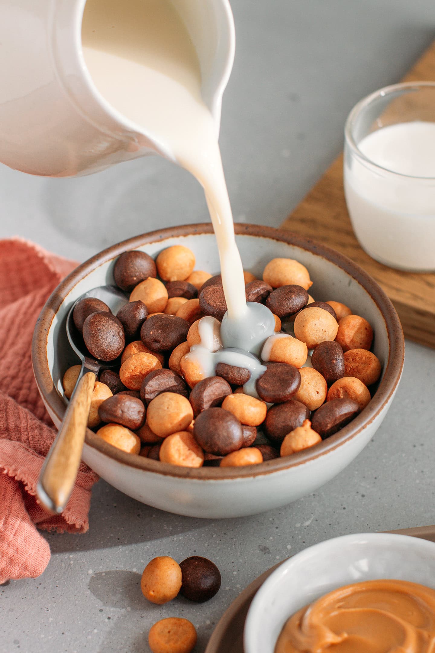 Pouring milk into a bowl containing chocolate and peanut butter cereal.