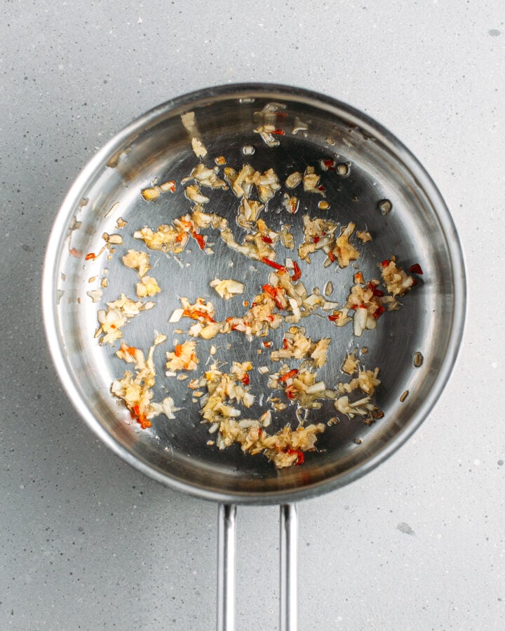 Sautéed garlic, ginger, and chili in a saucepan.
