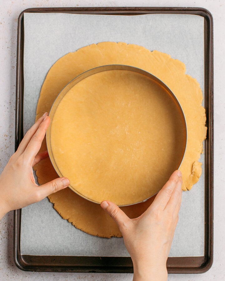 Cutting out a round of dough using a large pastry circle.
