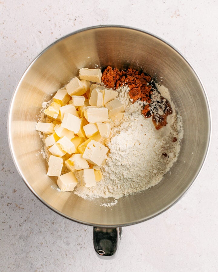 Diced butter, flour, brown sugar, and vanilla extract in a stand mixer bowl.