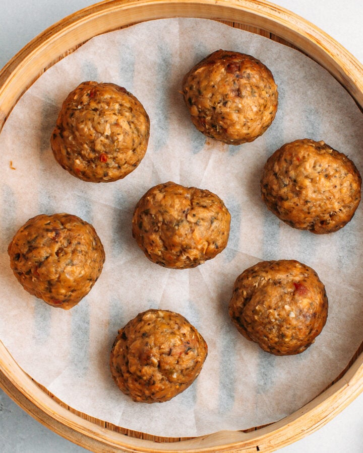 Cooked vegan meatballs in a bamboo basket steamer.