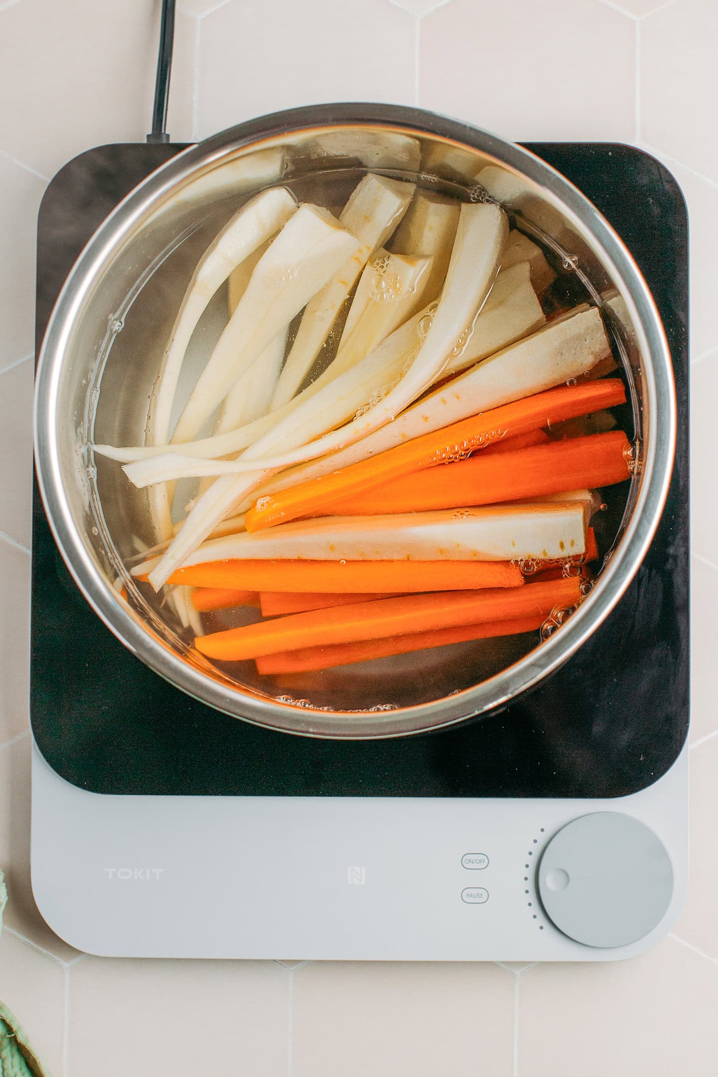 Sliced parsnips and carrots in a pot of boiling water.