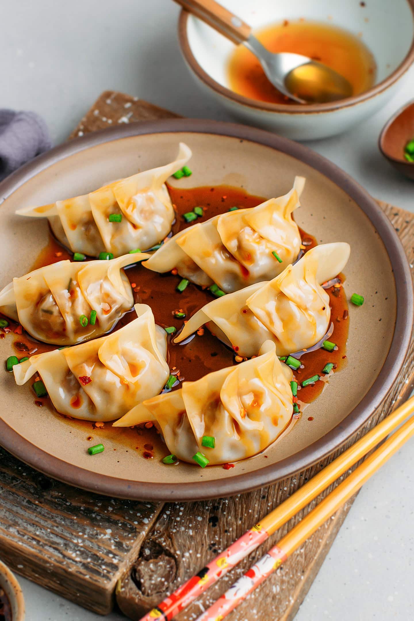 Six jackfruit dumplings topped with chopped scallions on a brown plate.