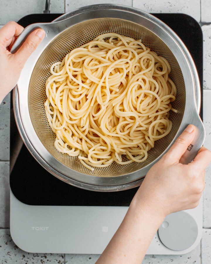 Draining cooked noodles using a colander.