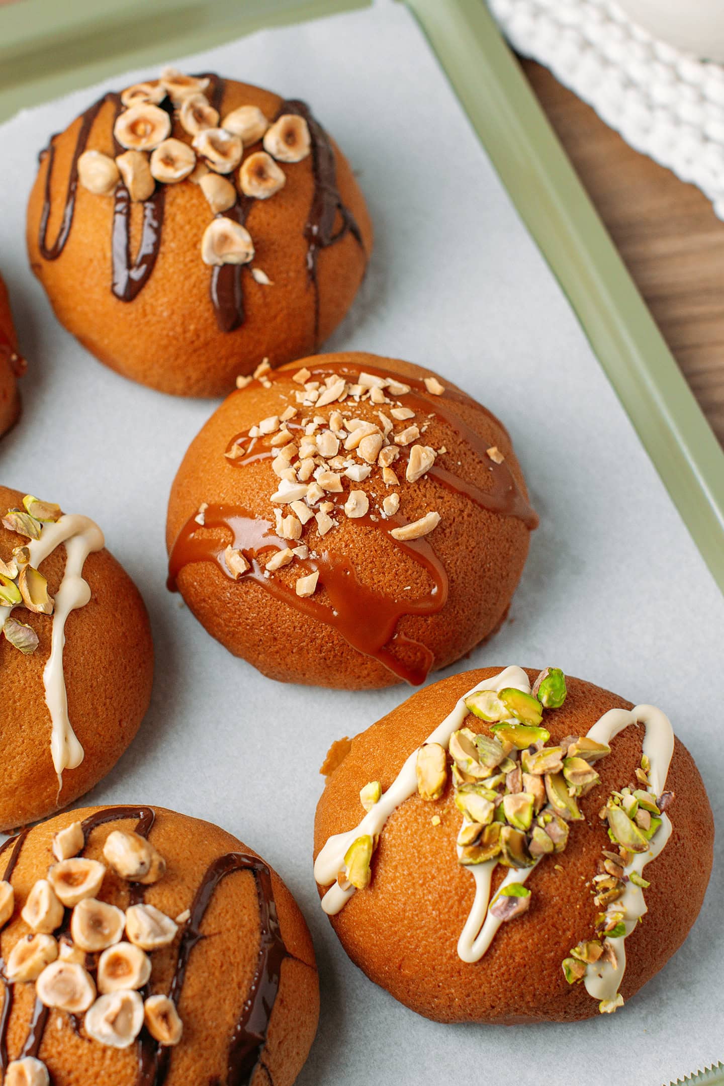 Six coffee buns garnished with nuts on a baking sheet.