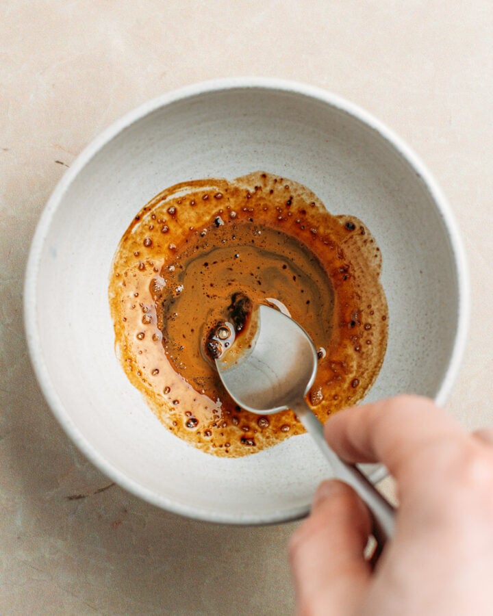 Diluting instant coffee with warm water in a small bowl.