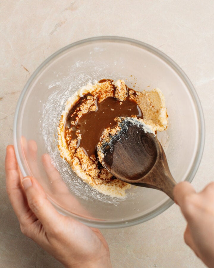Mixing creamed butter and sugar with coffee in a small glass bowl.